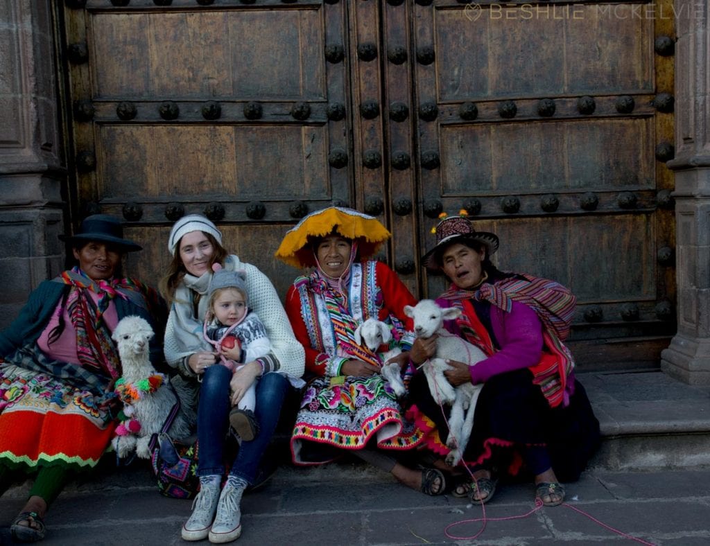 Peruvian ladies in traditional clothing sit on steps with Beshlie