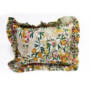 A rectangular frilly cushion with a yellow ruffled edge, featuring a hand block printed pattern of white cockatoos, yellow pomegranates, and green and pink floral branches on a white background.
