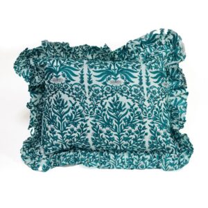 A handcrafted cushion with a teal and white fabric cover, featuring intricate floral and vine embroidery patterns, accented by a ruffled edge, set against a plain white background.