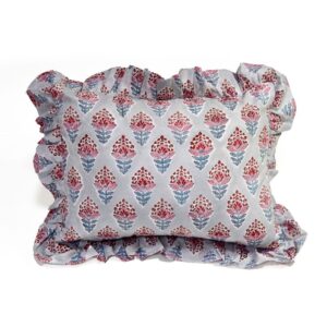 A handcrafted cushion with a grey fabric cover, featuring a repeating pattern of red and blue floral embroidery, accented by a ruffled edge, set against a plain white background.