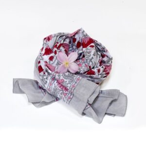 Hand block printed on organic cotton Pareo Beach Sarong with a soft grey base, intricate red, pink, and white floral patterns, delicate leaf motifs, and an ornate floral border, showcasing traditional craftsmanship for an elegant, eco-friendly beach accessory.