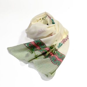Hand block printed on organic cotton scarf with a soft ivory base, intricate purple and green floral patterns, delicate leaf motifs, and a refined geometric border, showcasing traditional techniques and natural dyes for an elegant, eco-friendly accessory.