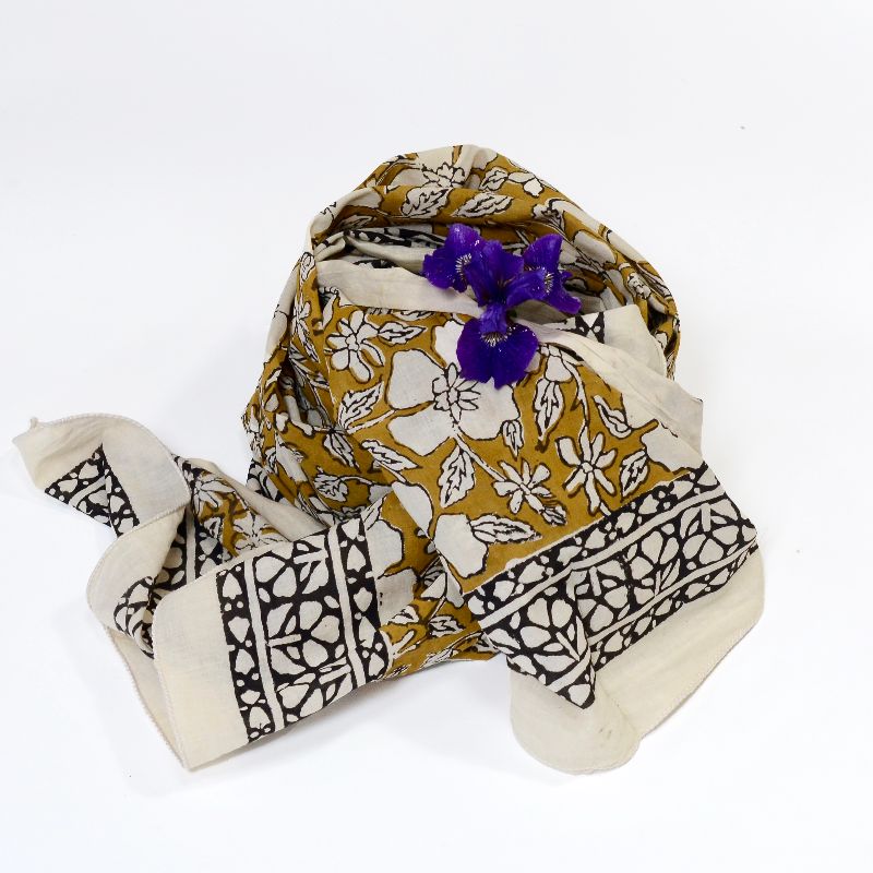 Hand block printed on organic cotton Pareo Beach Sarong with a mustard yellow base, intricate white floral patterns, leafy motifs, and a bold black and white geometric border, showcasing traditional craftsmanship for a stylish, eco-friendly beach accessory.