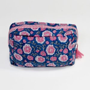 A handcrafted cosmetics bag with a blue fabric cover, featuring an intricate pattern of pink floral embroidery with green vines and leaves, accented by a red and white striped border and a pink tassel, set against a plain white background.