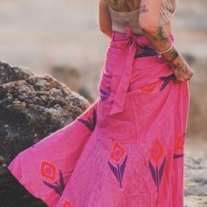 woman stands on rock in pink wrap skirt