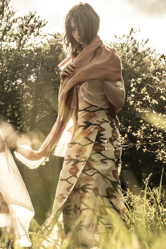 woman wears cream and terracotta wrap skirt in a sun-drenched meadow