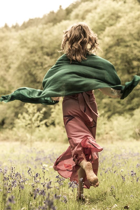 model running through a meadow wearing an ikat wrap skirt and cashmere shawl