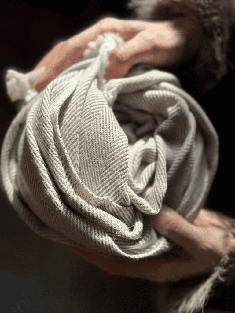 Hands holding a herringbone cashmere scarf