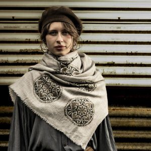 model drapped in mandala cashmere scarf against a rusty backdrop